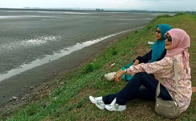 Dua wanita ini sedang duduk di depan lumpur Lapindo
